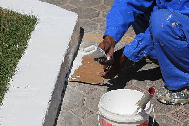 istock Workman with paint pot and brushes painting outside 472471576