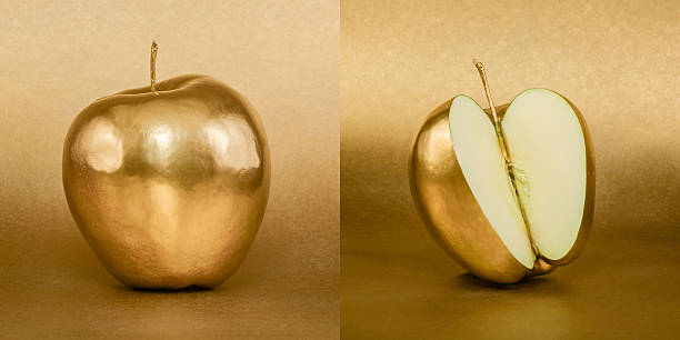 istock Whole and opened apple with golden peel on gold background 472473880