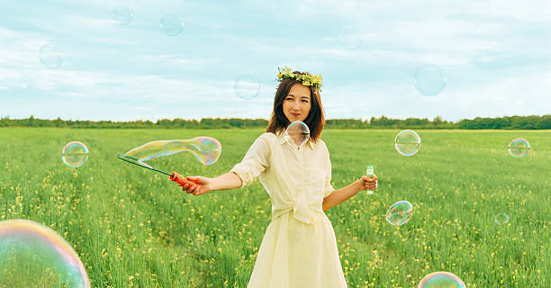 istock Smiling girl blowing soap bubbles in summer 472474876