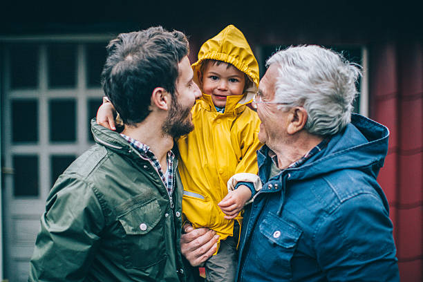 Three generations Photo of smiling little boy with his father and grandfather raincoat photos stock pictures, royalty-free photos & images