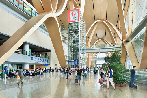 Kunming, China - June 30, 2014: Spacious interior of Kunming Changshui International Airport with travelers walking around. It is the primary airport serving Kunming, the capital of Yunnan Province, China.
