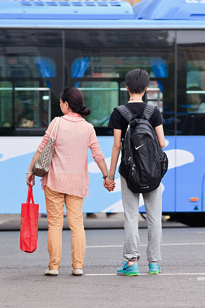 Mother takes her son by the hand while crossing street. Nanjing, China - May 25, 2014: Mother takes her son by the hand while crossing the street. Although, the status of women in China is getting better, there are still many parents who prefer having a male child. nike air photos stock pictures, royalty-free photos & images