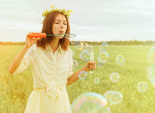 istock Young woman blowing soap bubbles in summer 472476444
