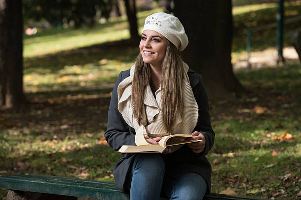 istock Beautiful Young Girl Reading A Book In Park 472477002