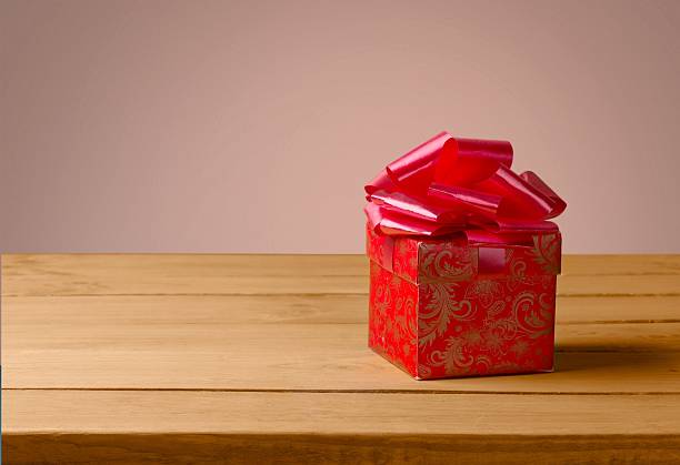 istock Gift. Small gift box with pink ribbon on wooden table 472478638