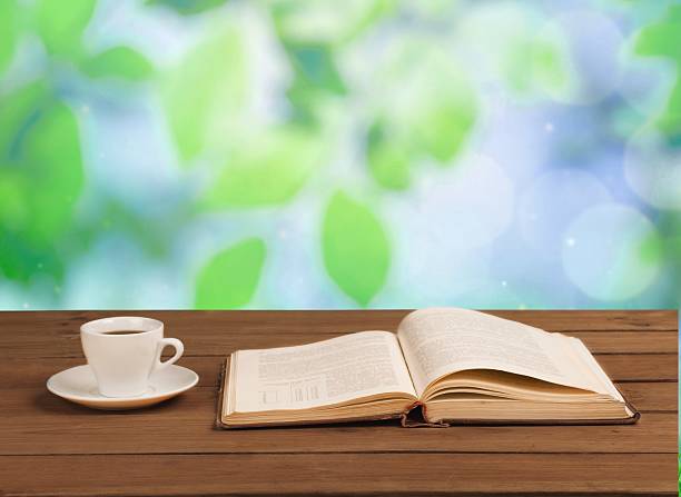 istock Cup of coffee and a book on a wooden table 472479018
