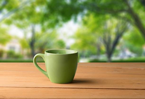 istock Backdrop. Green mug on wooden table over grunge background 472479680