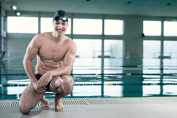 istock Young muscular swimmer with goggles and swim cap 472481252