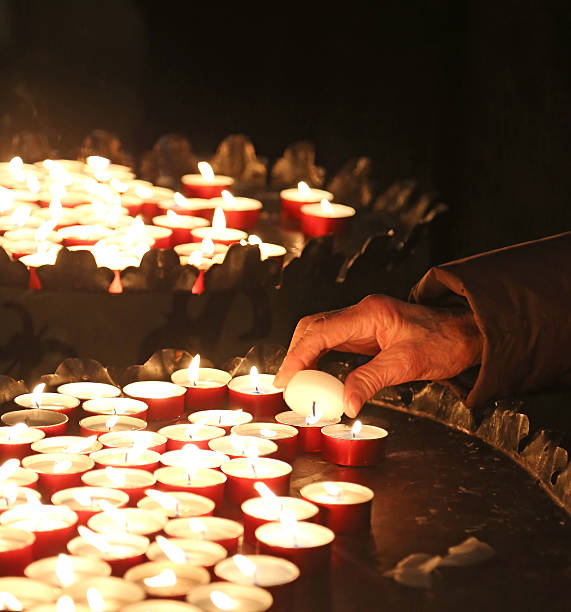 la mano de una mujer de edad avanzada luces de las velas para rezar - nun praying clergy women fotografías e imágenes de stock