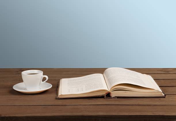 istock Cup of coffee and a book on a wooden table 472481918
