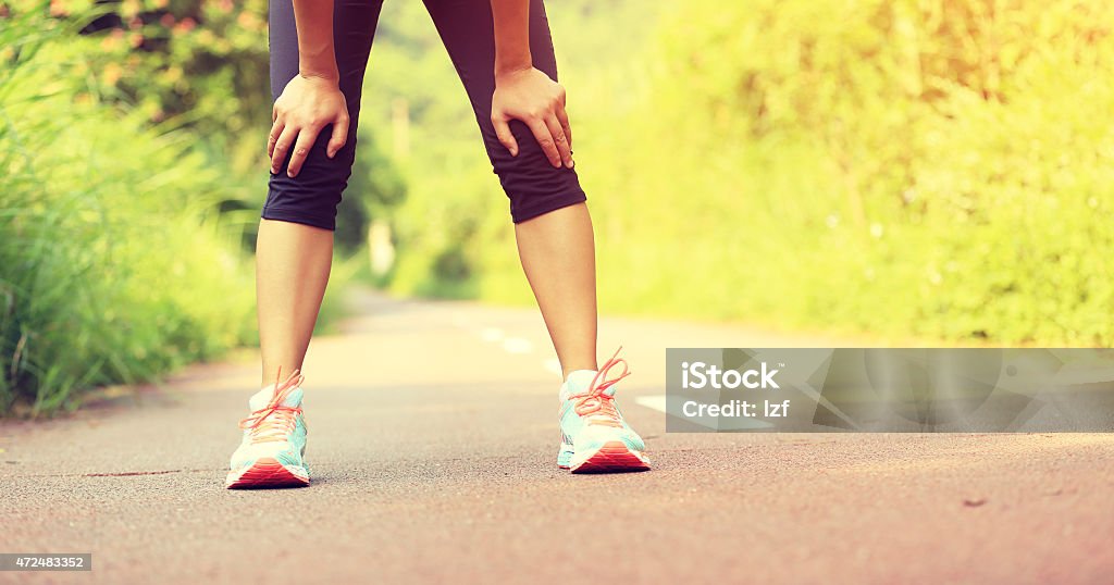 tired female runner taking a rest after running hard tired female runner taking a rest after running hard in countryside road. sweaty athlete after marathon training in country road. 2015 Stock Photo