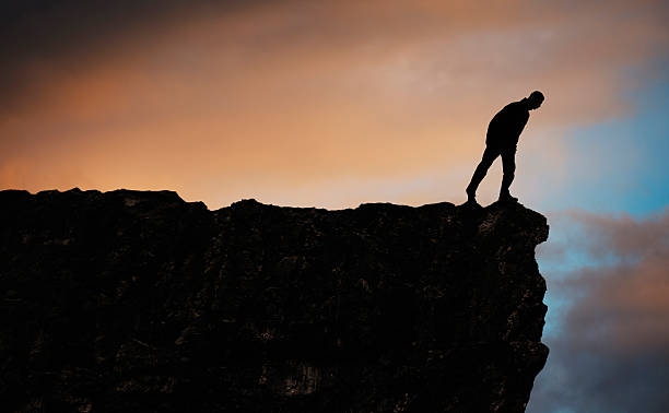 istock Silhouette of man on mountain top looking down 472484416