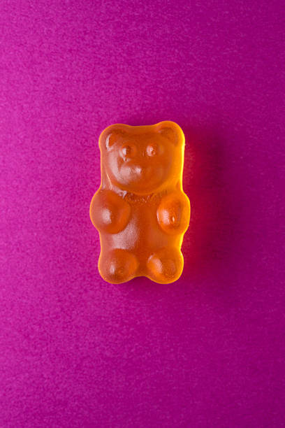 istock Orange gummy bear candy on purple paper 472485928
