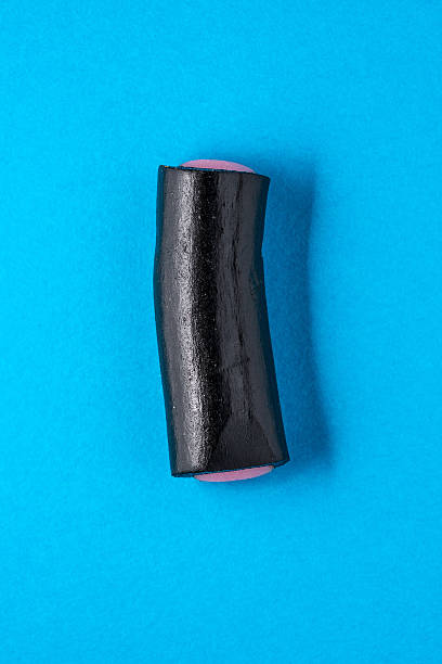 istock Black liquorice candy on blue turquoise paper 472485932