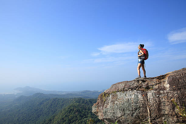 istock cheering young woman hiker at mountain peak 472486750