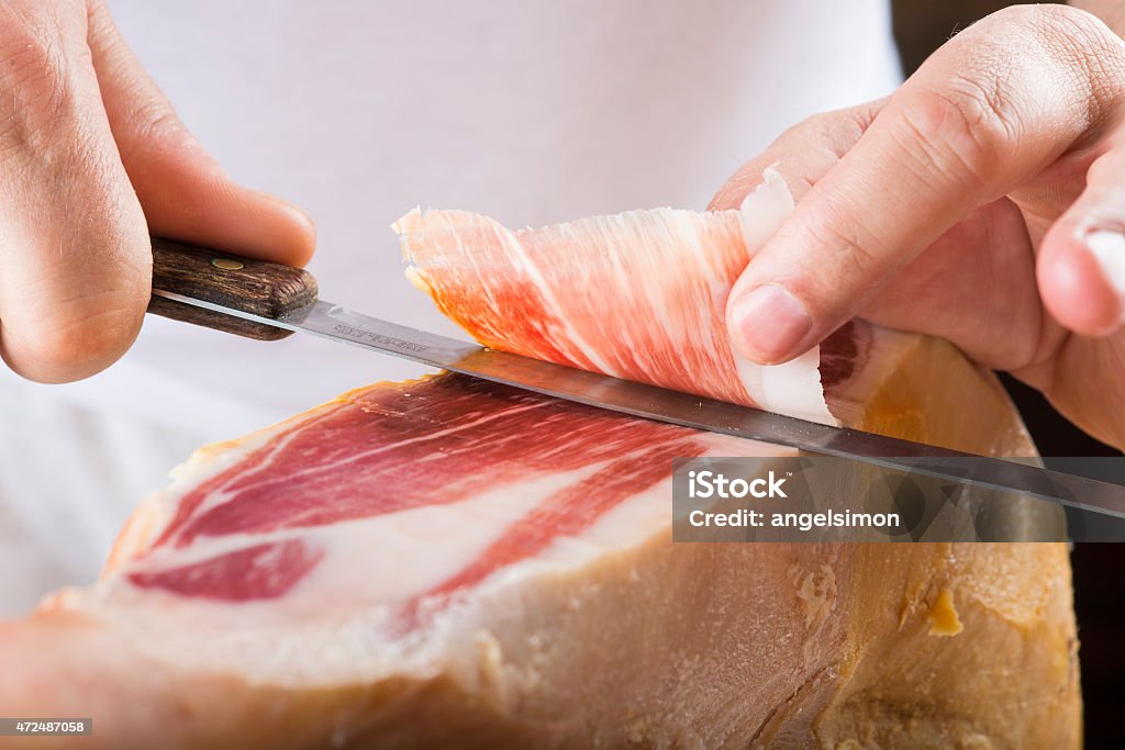 Professional cutting of serrano ham Professional cutter carving  slices from a whole bone-in serrano ham 2015 Stock Photo