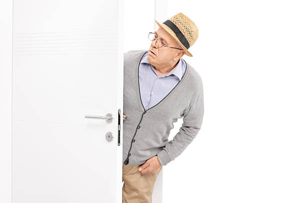 Curious senior looking at something behind a door