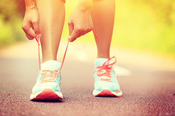 istock Young female runner tying her shoe on red asphalt 472488352
