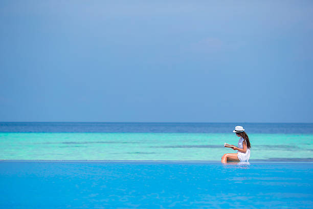 istock Young girl reading book near swimming pool 472492456