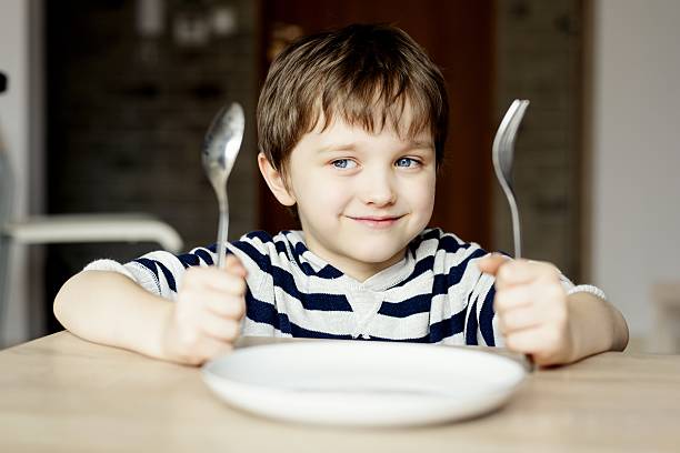 heureux petit garçon en attente pour le dîner. - fork table knife silverware spoon photos et images de collection