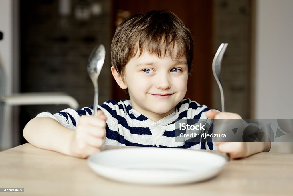 Happy little boy waiting for dinner. Happy little boy waiting for dinner. Holding a spoon and fork in the hand Child Stock Photo