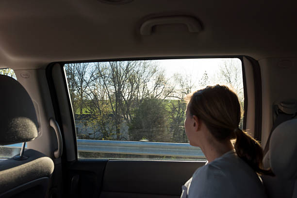 Young woman in backseat looking out window on highway