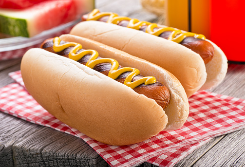Delicious barbecued hot dogs on a rustic picnic table.