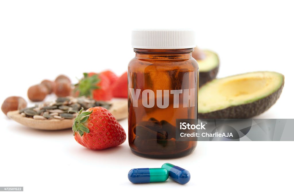 Anti age pill of youth Anti-aging pills surrounded by nutritious superfoods including avocado, pumpkin seeds and berries 2015 Stock Photo