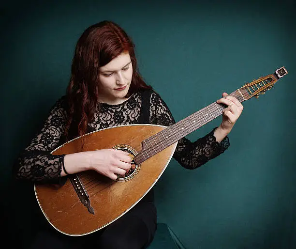 young woman playing vintage lute instrument with added filter
