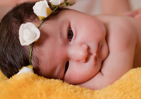 new born baby lie on the bed with flowers crown