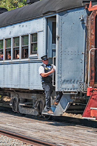 Sunol, California, USA - May 3, 2015: This brakeman is checking the arrival with the train coming to the station in Sunol there are also many passengers on the passenger car as well as the remainder of this train that carries visitors from Sunol to Niles along the Niles Canyon Railway and on this May day it was a great time.
