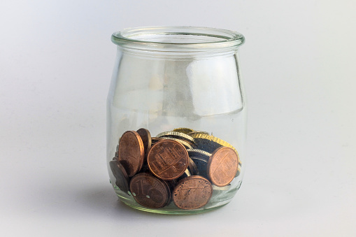Home finances and savings idea with various coins in a jar.