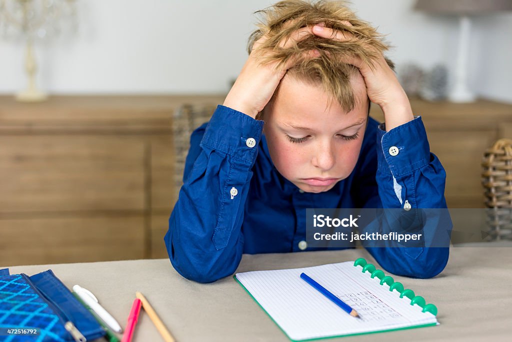 stressful homework boy struggling with his homework, holding his hands in his hair Child Stock Photo