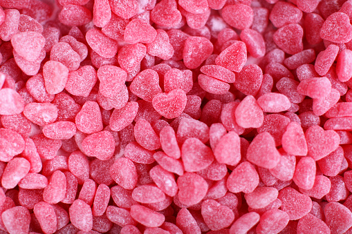 This is a full frame close-up image of lots of red gummy candy (or gumdrops) in the shape of a heart. Gummy Candy Hearts background.