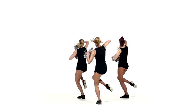 Girl in black costume  with pom-poms dancing on  white background, slow motion, smiling at the camera