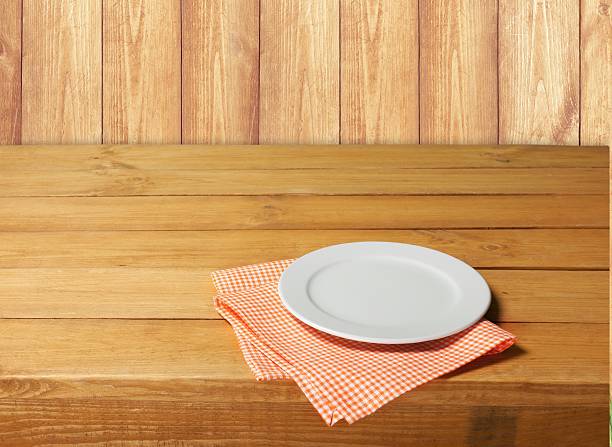 istock Empty white plate on wooden table over red grunge background 472533138