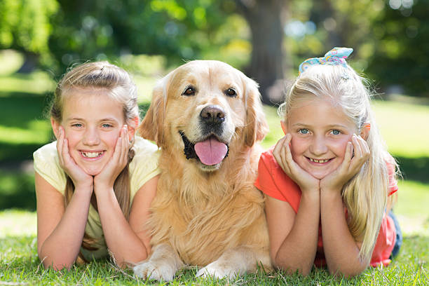 istock Happy sisters smiling at camera with their dog 472540200