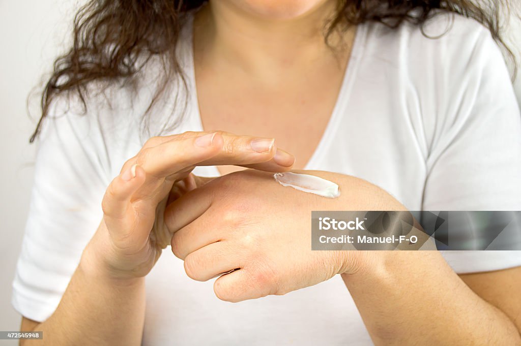 Enhancing her natural beauty Cropped image of a young woman putting moisturizer onto her finger 2015 Stock Photo
