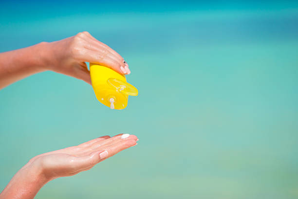 istock Female hands with suncream bottle background blue sea 472552234