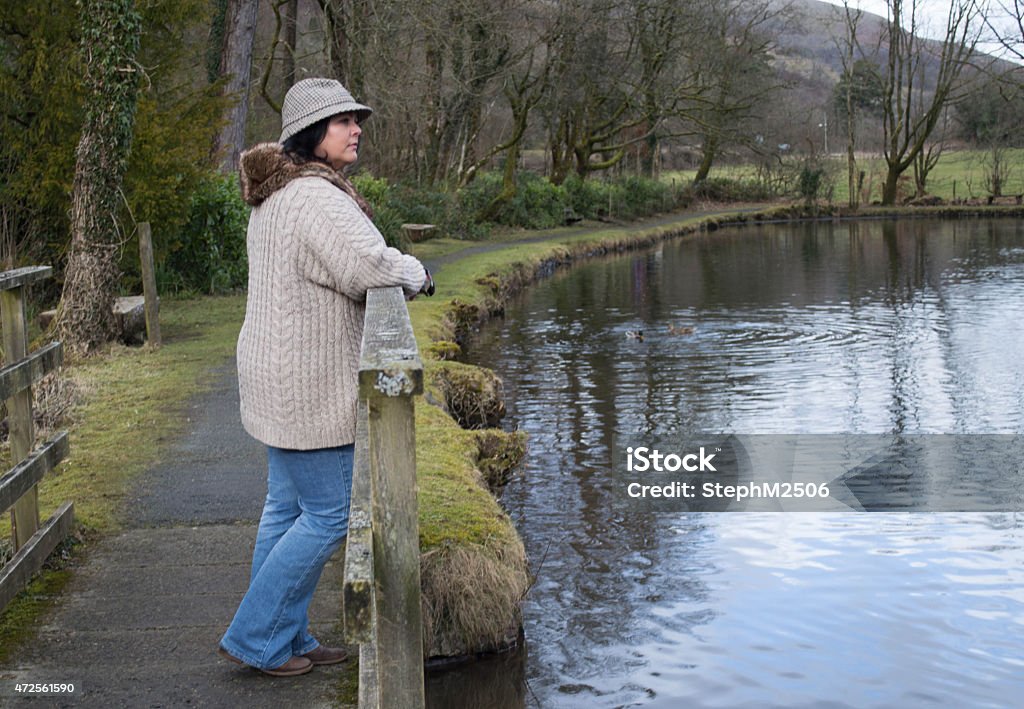 Mature woman standing on bridge looking at view Portrait of a mature woman standing on bridge, looking into distance, admiring view 2015 Stock Photo