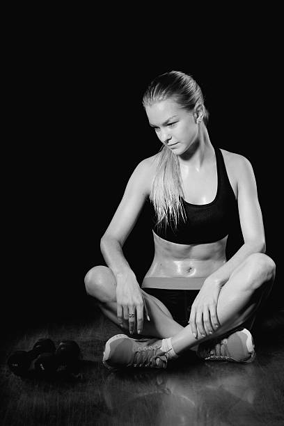 istock Female fitness model resting. Black background 472576502