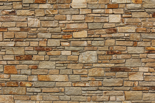 A stone wall of the Parthenon in Greece, against blue sky.