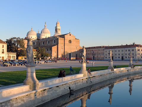 Padua, Italy - April 7, 2015: Daytime glimpse of the Abbey of Santa Giustina, with tourists and passers of urban park Prato della Valle in Padua.