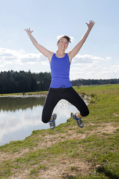 young woman in workout clothes jumping outdoors