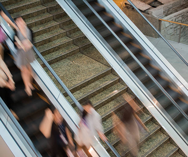 istock Group of businesspeople moving down on escalator in office. blur 472586222