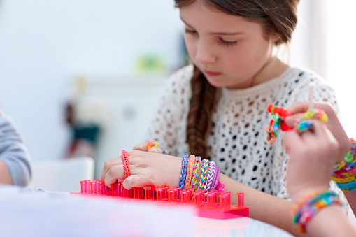 Innocent young girl making rubber band bracelet with a loom bands