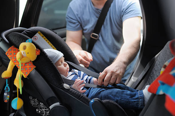 Infant boy in car seat being put in back of car by father Father fasten his little son in car seat genderblend stock pictures, royalty-free photos & images