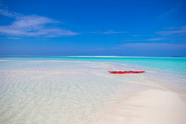 istock Red surfboard on white sandy beach with turquoise water 472594722