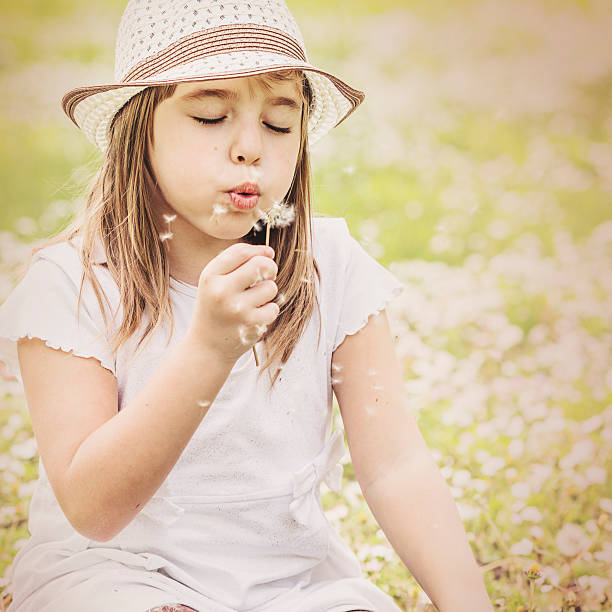 istock Little girl blowing a dandelion 472596216
