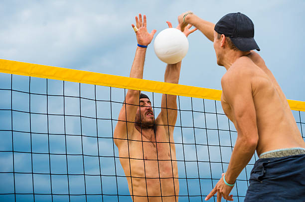 vista lateral de atractiva voleibol playero acción en el net - volleyball volleying human hand men fotografías e imágenes de stock